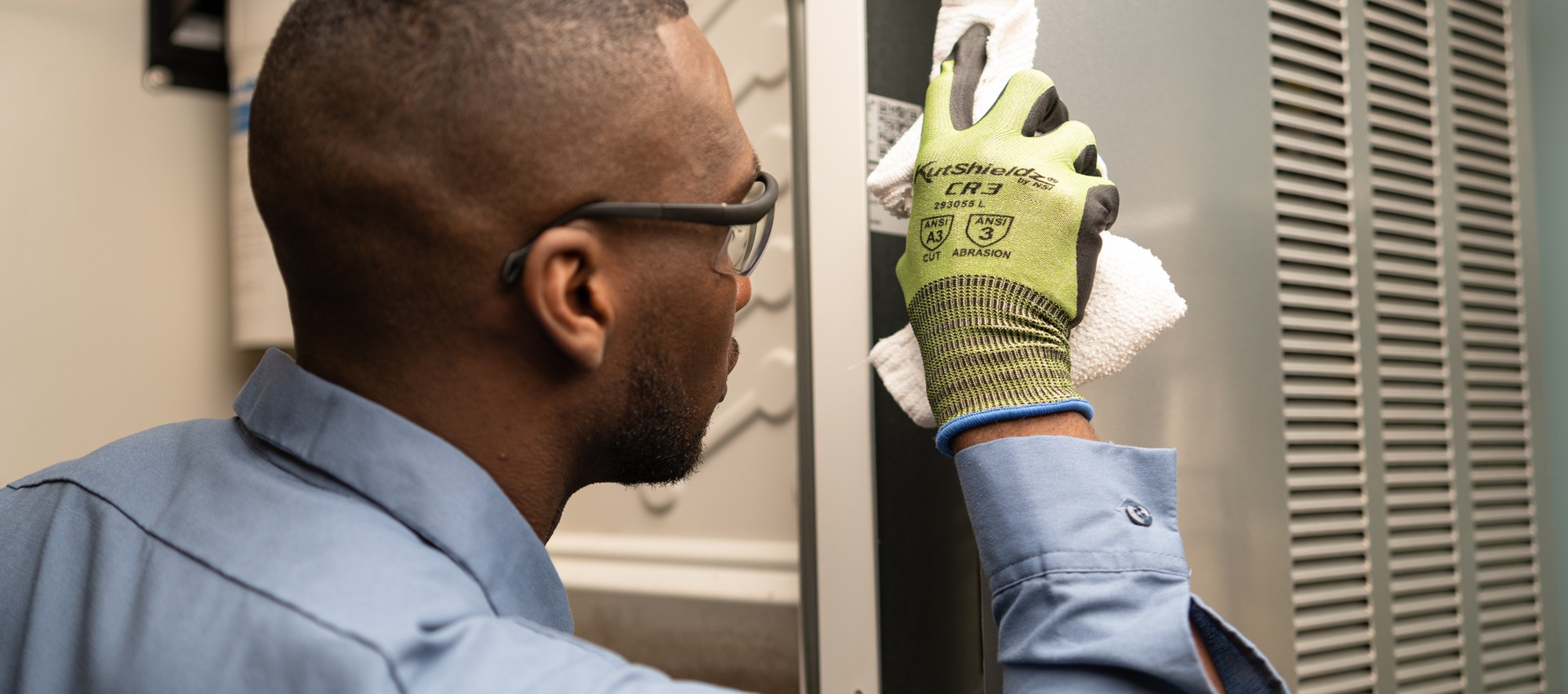 Technician in safety glasses and work gloves cleaning the inside of a commercial refrigerator