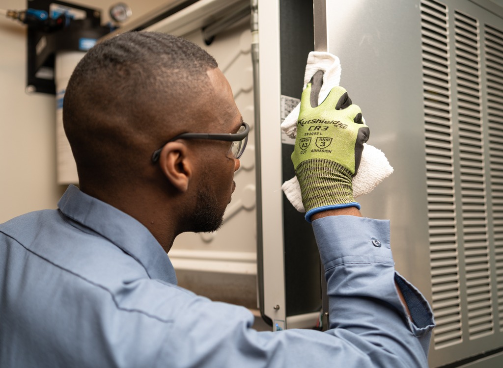 Technician in safety glasses and work gloves cleaning the inside of a commercial refrigerator