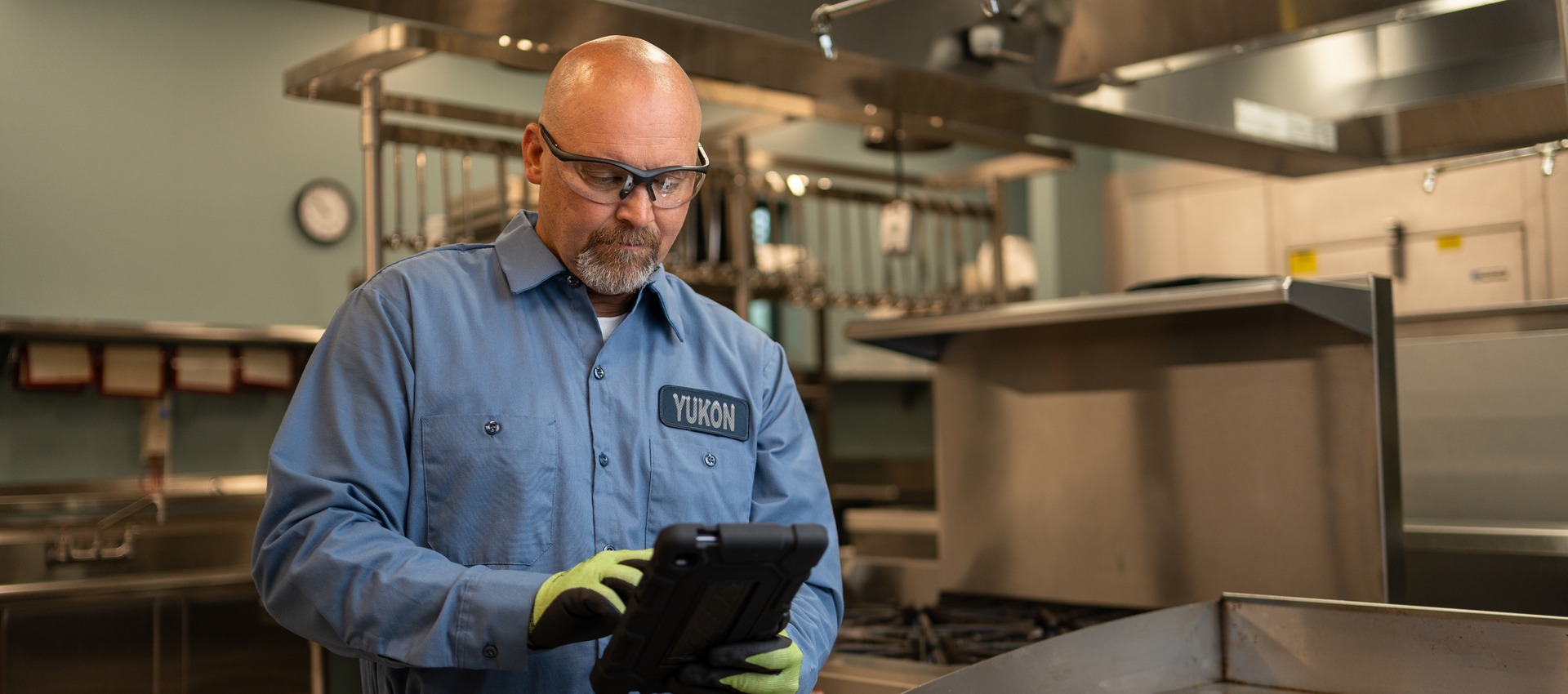 Technician in uniform reviewing a tablet in a commercial kitchen