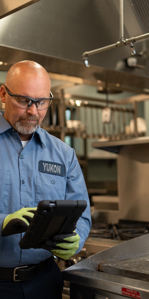 Technician in uniform reviewing a tablet in a commercial kitchen