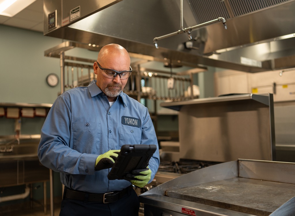 Technician in uniform reviewing a tablet in a commercial kitchen