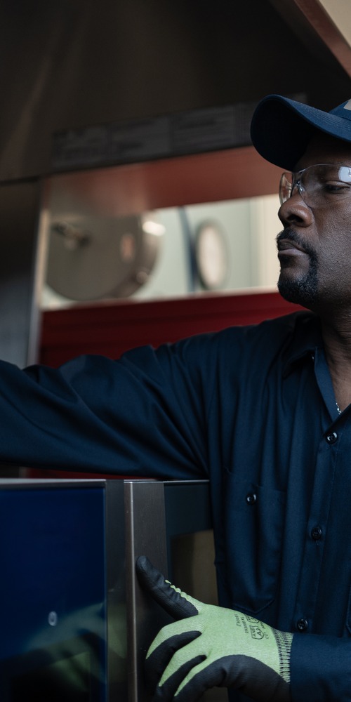 Yukon Refrigeration technician in a cap and safety glasses servicing commercial kitchen equipment