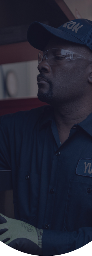 Yukon Refrigeration technician in a cap and safety glasses servicing commercial kitchen equipment