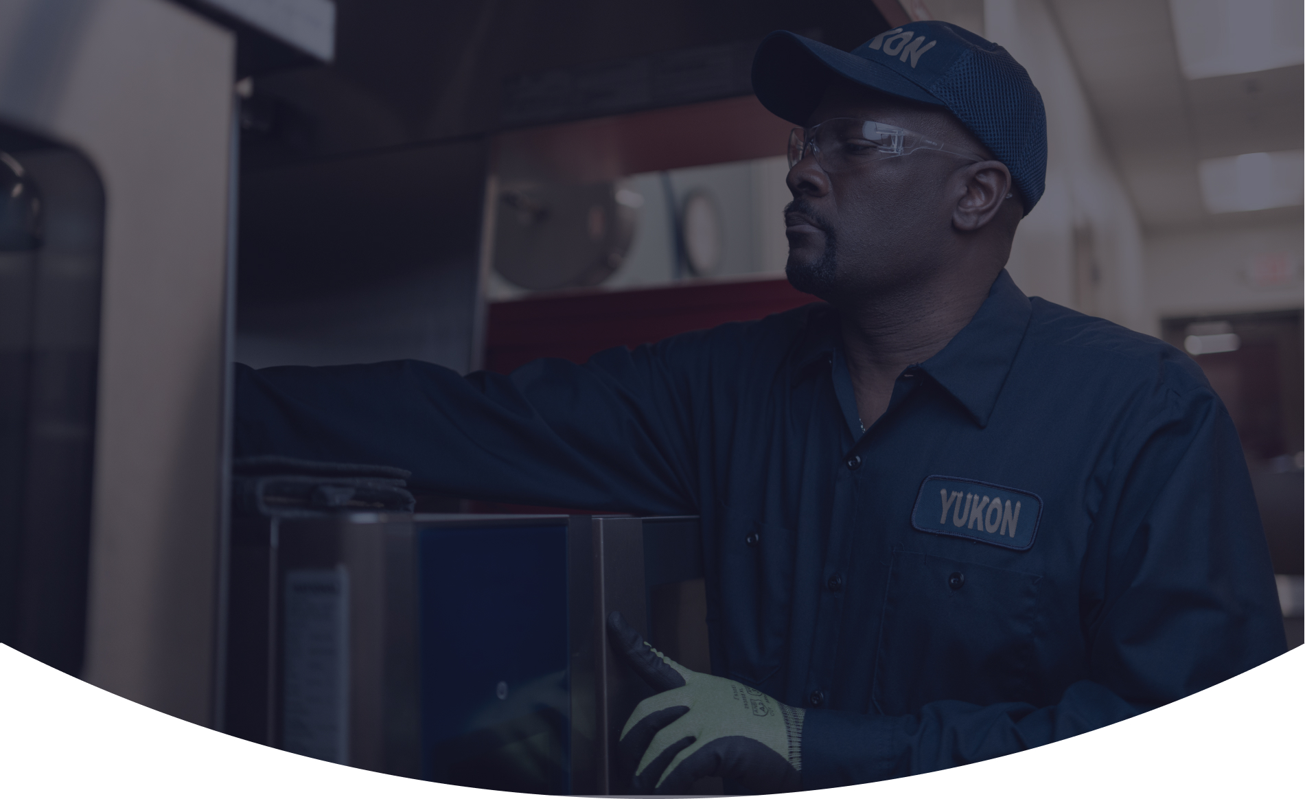 Yukon Refrigeration technician in a cap and safety glasses servicing commercial kitchen equipment